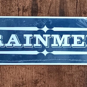 May include: A blue metal sign with white lettering that reads "FOR TRAINMEN ONLY".