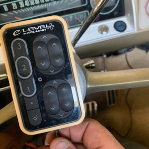 May include: A beige and black remote control with the text "e-LEVEL by ACCUAIR" and a series of up and down arrows. The remote control has three numbered buttons: 1, 2, and 3. The button labeled "C" is in the center of the remote control.
