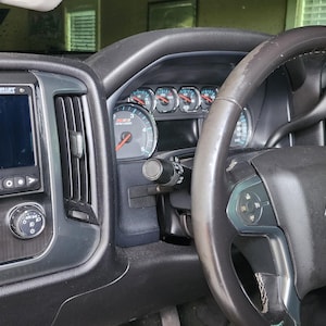 May include: Interior view of a black Chevrolet truck. The steering wheel is black leather with a gold Chevrolet emblem. A digital display screen is visible on the dashboard, along with gauges and air vents.