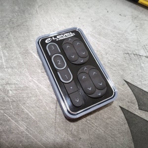 May include: A black remote control with the text "E-Level by Accuair" on the top. The remote has a series of buttons with arrows pointing up and down, and numbers 1, 2, and 3.