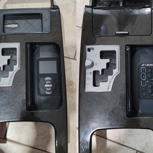 May include: Two black car center console panels with different accessories. The left panel has a black electronic device with a screen and the text "Bullet" on it. The right panel has a black remote control with the text "C-Level" and numbered buttons.