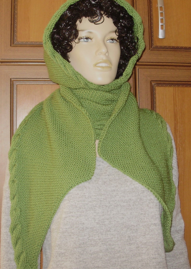 May include: A green knitted scarf with a hood. The scarf is made of a soft, textured yarn and has a simple, elegant design.