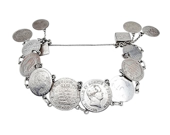 May include: A silver bracelet featuring a series of antique coins of varying sizes and designs. The coins are linked together with small chain segments. The bracelet has a clasp closure and several smaller coins dangle from the chain.