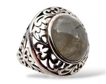 Pode incluir: Um anel de prata com uma pedra preciosa cinza oval. O anel tem um design ornamentado e vazado ao redor da pedra preciosa e da banda. A pedra preciosa tem aproximadamente 2 cm de comprimento.