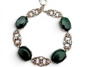 May include: An antique bracelet featuring oval, dark green gemstones set in ornate, silver-toned links. The bracelet has a secure clasp and is displayed against a white background. The gemstones are approximately 0.75 inches in length.