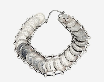 May include: A silver bracelet made of linked coins. The coins are all silver and have a raised profile of a person's face on them.