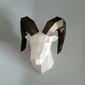 May include: A white papercraft ram head with large, brown, folded paper horns. The ram's head is made of folded paper and has a 3D effect.
