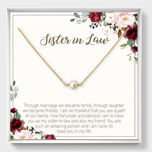 May include: A white card with a gold necklace and a single pearl pendant. The card has a floral design and the text "Sister in Law" in brown lettering. The text on the card reads: "Through marriage we became family, through laughter we became friends. I am so thankful that you are a part of our family. How fortunate and blessed I am to have you as my sister-in-law and also my friend. You are such an amazing person and I am lucky to have you in my life."