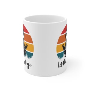 May include: White ceramic mug with a retro sunset design and the text "Let the good shit go" on one side and "Let the good shit go" on the other side.