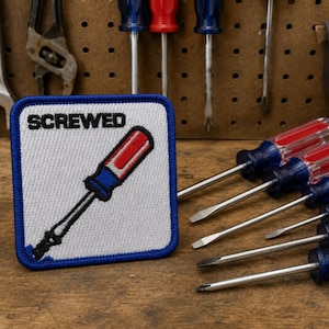 May include: A square embroidered patch with a white background and a blue border. The patch features a graphic of a red, white, and blue screwdriver and the word SCREWED in black capital letters. The patch is positioned near several screwdrivers.