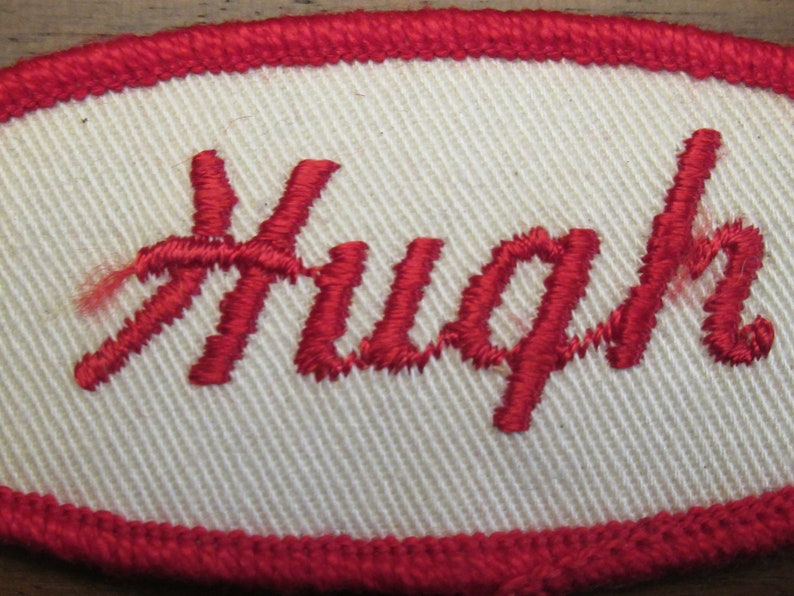 faded work uniform patch with Hugh in red stitching Hugh white