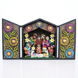 May include: A colorful, hand-painted nativity scene in a triptych design. The wooden frame features floral and vine details in shades of blue, yellow, pink, and green. The central scene depicts the holy family and other figures in traditional attire.