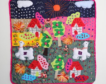 May include: A colourful embroidered wall hanging depicting a whimsical scene of houses, trees, and llamas. The background is a dark blue with white clouds and rain. The houses are white with red roofs and the trees are green with pink flowers. The llamas are white with brown spots.
