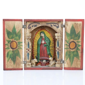May include: A wooden religious triptych featuring a carved image of the Virgin Mary with a green cloak and red dress, surrounded by a yellow halo. The side panels are decorated with green floral designs and a red border. The central panel includes two lambs and an angel.