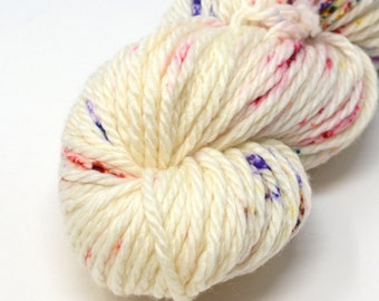 May include: A skein of white yarn with colourful flecks of pink, red, purple, and yellow.