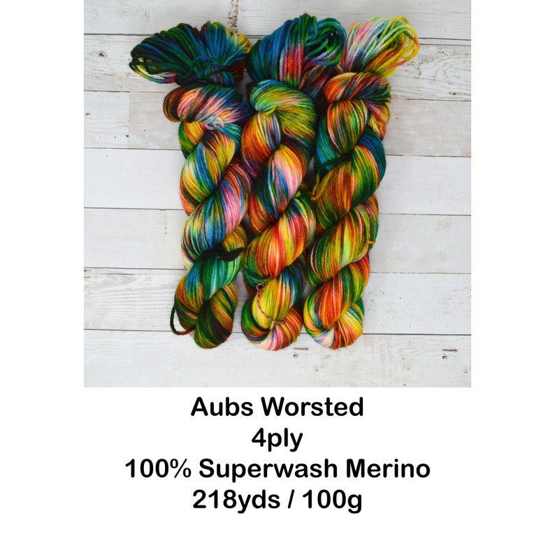 Puede incluir: Tres ovillos de hilo de colores en un arco&iacute;ris de colores, incluyendo verde, azul, amarillo, naranja y rojo. El hilo est&aacute; etiquetado "Aubs Worsted 4ply 100% Superwash Merino 218yds / 100g".