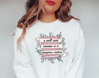 May include: White sweatshirt with a pink book graphic and the text "a well read woman is a dangerous creature" surrounded by floral illustrations.