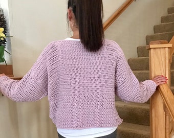 May include: A light purple crocheted sweater with long sleeves. The sweater is loose fitting and has a relaxed, casual style.