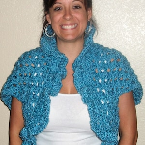 May include: A teal blue crocheted shrug with short sleeves. The shrug is open in the front and has a ruffled collar.