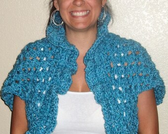 May include: A teal blue crocheted shrug with short sleeves. The shrug is open in the front and has a ruffled collar.