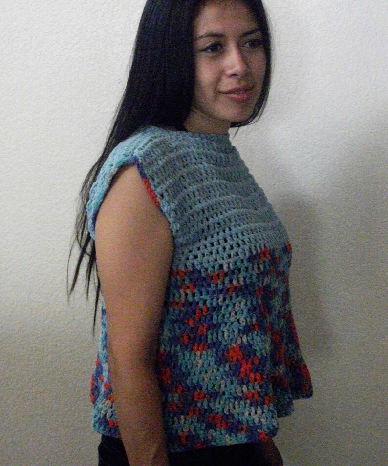May include: A sleeveless crochet top with a blue, red, and white color pattern. The top has a loose fit and a round neckline.