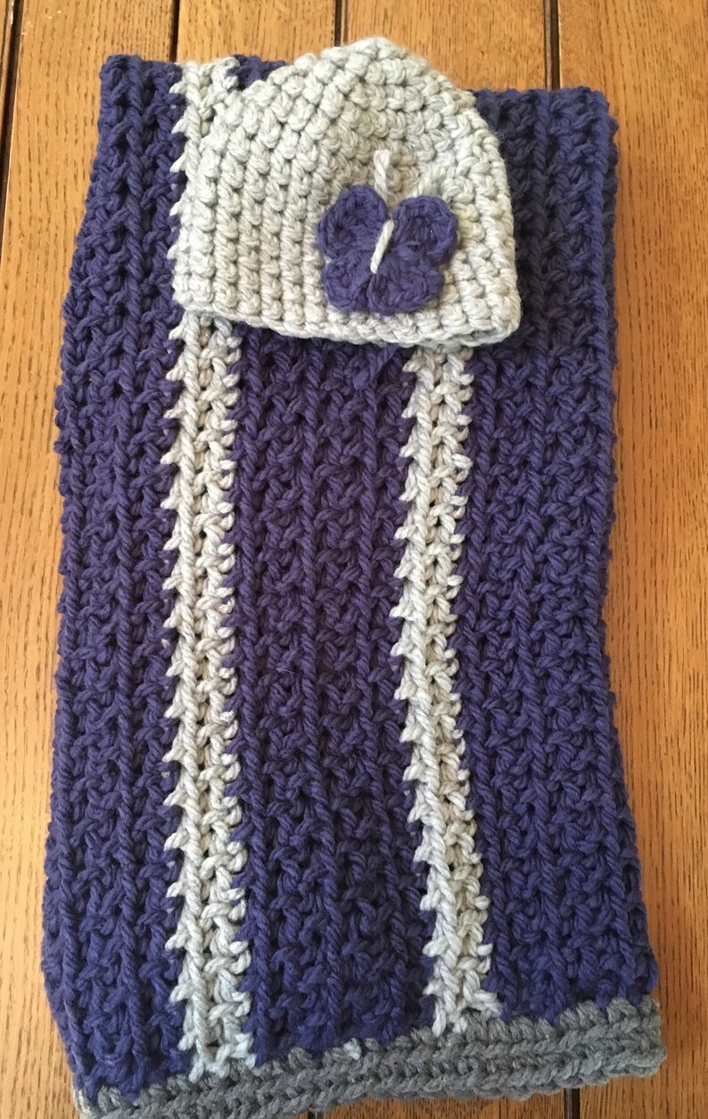 May include: A purple and gray striped crocheted baby blanket with a matching gray crocheted hat with a purple crocheted butterfly on top.