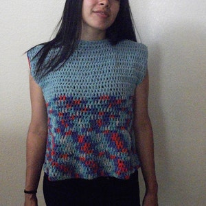 May include: A blue crocheted sleeveless top with a geometric pattern in shades of blue, red, and white.