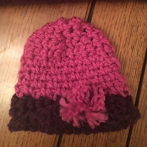 May include: A pink and purple crocheted hat with a fluffy pom-pom.