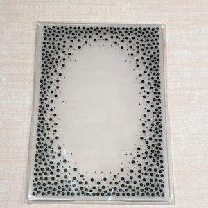 May include: Clear plastic sheet with a black oval frame surrounded by a pattern of small black hexagons.