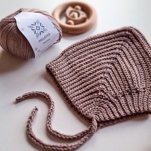 Pu&ograve; includere: Un berretto per neonato in crochet rosa chiaro con lacci abbinati. Il berretto &egrave; realizzato con una maglia testurizzata e ha una corona a punta. La matassa di lana &egrave; etichettata "MILLAMIA SWEDEN".