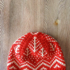 Puede incluir: Gorro de punto de crochet rojo y blanco con un patr&oacute;n geom&eacute;trico. El gorro est&aacute; hecho con un hilo suave y tiene una sensaci&oacute;n c&aacute;lida y acogedora.