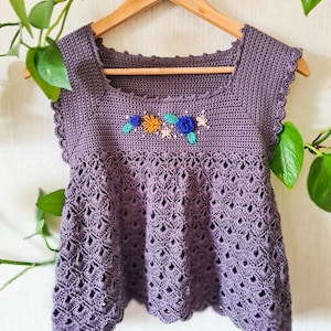 May include: A purple crocheted top with a scalloped hem and embroidered flowers in shades of blue, green, orange, and yellow.