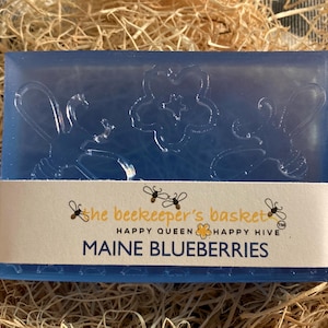 May include: A blue bar of soap with a bee design and the text "the beekeeper's basket" and "HAPPY QUEEN HAPPY HIVE" and "MAINE BLUEBERRIES".