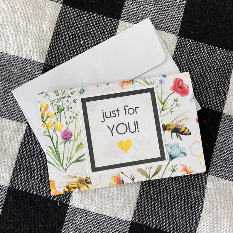 May include: A floral greeting card with the text "just for YOU!" and a yellow heart. The card features illustrations of bees, flowers, and greenery, and comes with a white envelope.