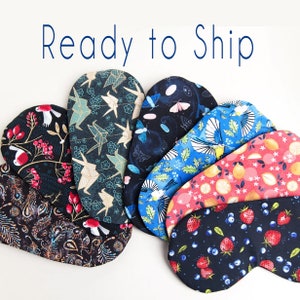 May include: Eight different eye masks made of fabric with various patterns. The patterns include birds, flowers, origami cranes, and geometric designs. The eye masks are all ready to ship.