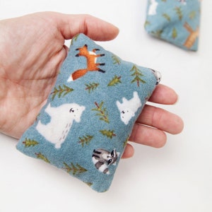 May include: A blue fabric pouch with a white polar bear, fox, and raccoon pattern. The pouch is filled with rice or beans and can be used as a heating pad.