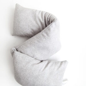May include: A gray and white herringbone patterned lumbar pillow. The pillow is folded in half and is lying on a white surface.