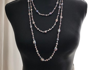 Può includere: Una collana di perle multifilo con perle grigie e viola iridescenti. La collana è esposta su un manichino nero.