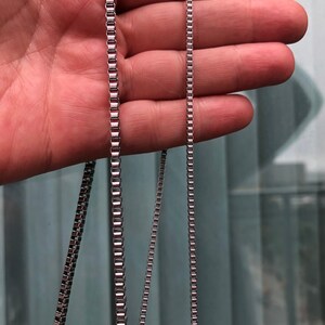 May include: Three silver chains of different lengths, shown against a blurred background.