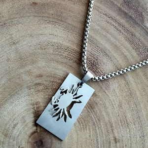 May include: A silver chain necklace with a rectangular pendant featuring a cutout design of a crab.