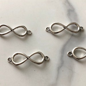 May include: Four silver infinity symbol charms with jump rings. These charms are perfect for jewellery making or adding to a keychain.