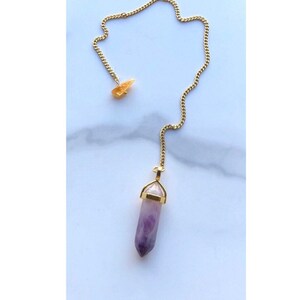May include: A gold chain with a purple amethyst crystal pendulum and a small yellow crystal charm.