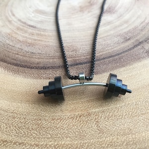 May include: A black chain necklace with a silver barbell pendant. The barbell is made of two black weights connected by a silver bar.