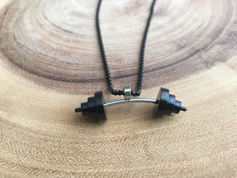 May include: A black chain necklace with a silver barbell pendant. The barbell is made of two black weights connected by a silver bar.