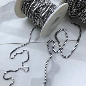 May include: Two spools of silver chain, one on each spool, with two lengths of chain laid out on a white surface.