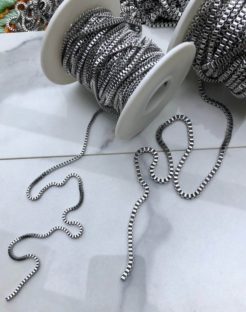 May include: Two spools of silver chain, one on each spool, with two lengths of chain laid out on a white surface.
