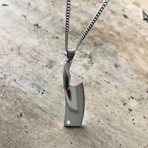 May include: A silver chain necklace with a silver pendant shaped like a butcher knife.