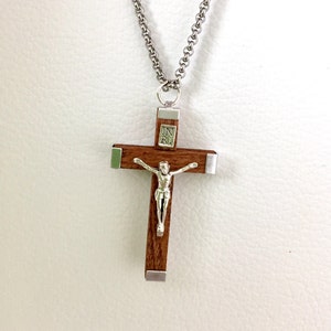 May include: A wooden crucifix pendant with a silver Jesus figure and a silver chain. The crucifix has a silver plaque with the inscription "INRI" on the front.