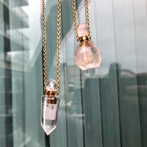 May include: Two gold chain necklaces with crystal perfume bottles. One bottle is a clear quartz point and the other is a pink rose quartz.