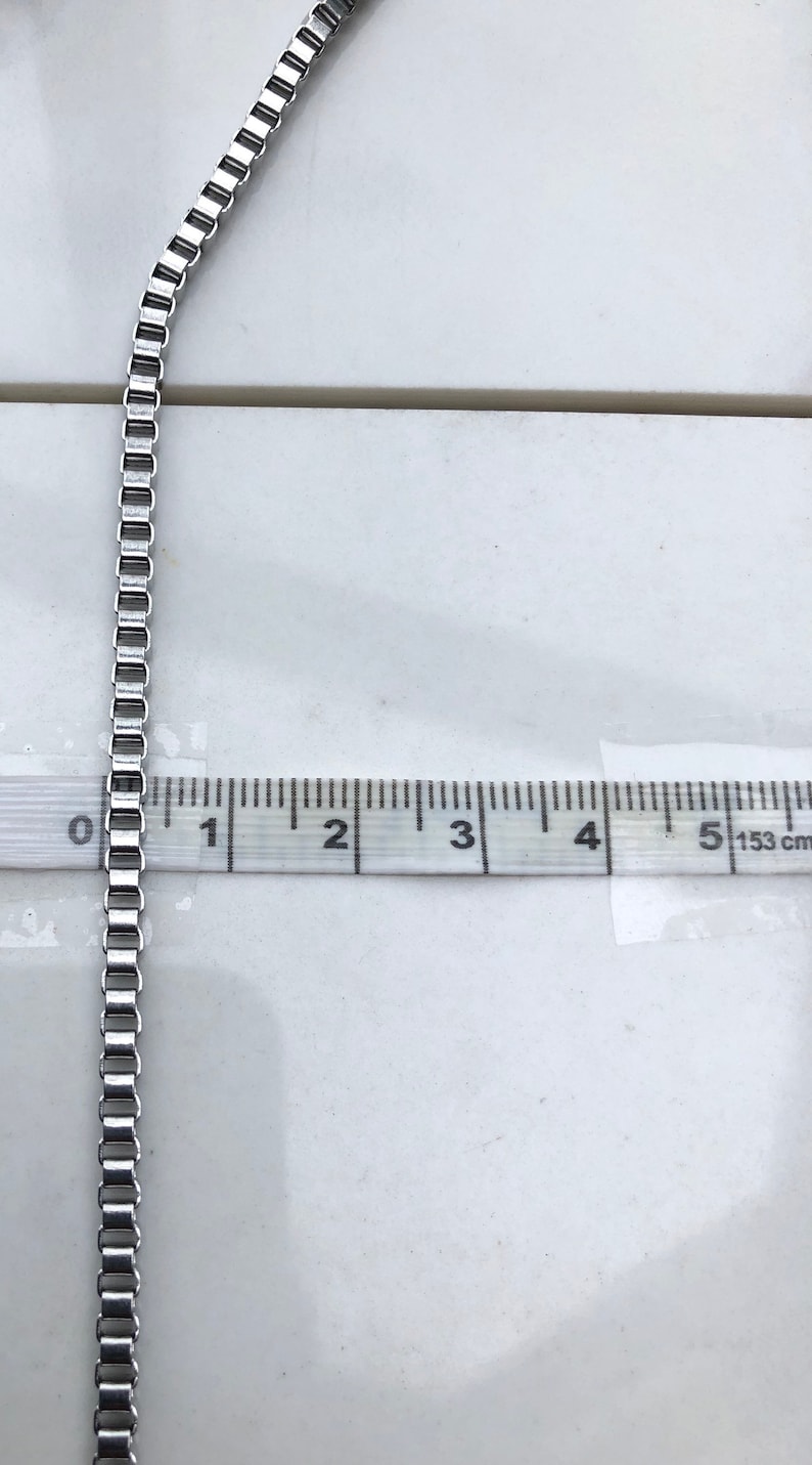 May include: A silver chain necklace measuring 5 inches long. The chain is made of small, square links.